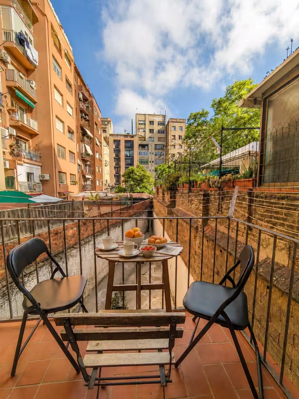 The apartment’s private balcony with a breakfast table overlooking an Eixample courtyard